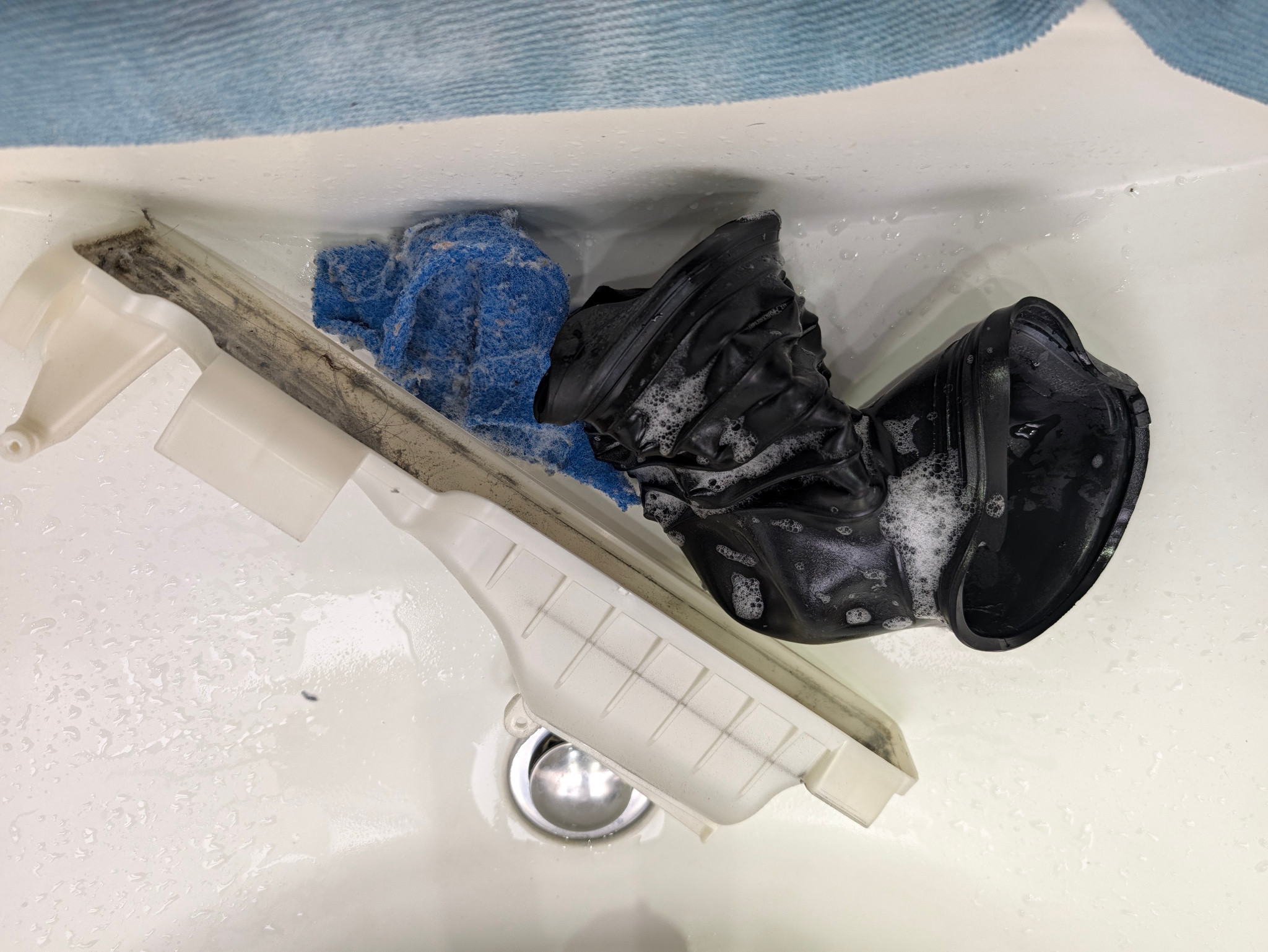 洗浄中の黒い蛇腹ホースと白い部品